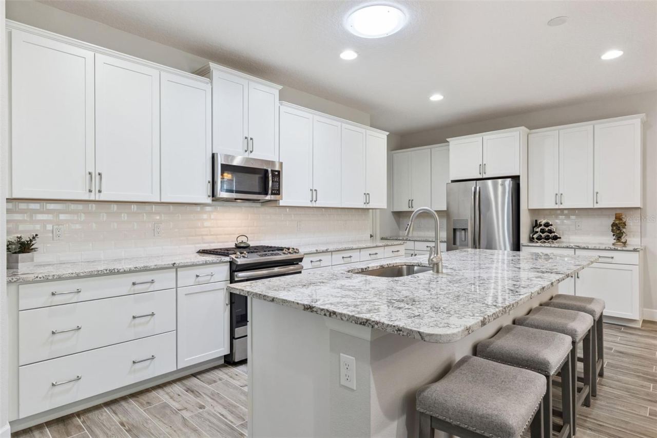 Photo 4 of 20: The kitchen features lovely white cabinets, stunning granite, stainless steel appliances, large island, and a Solatube® Skylight