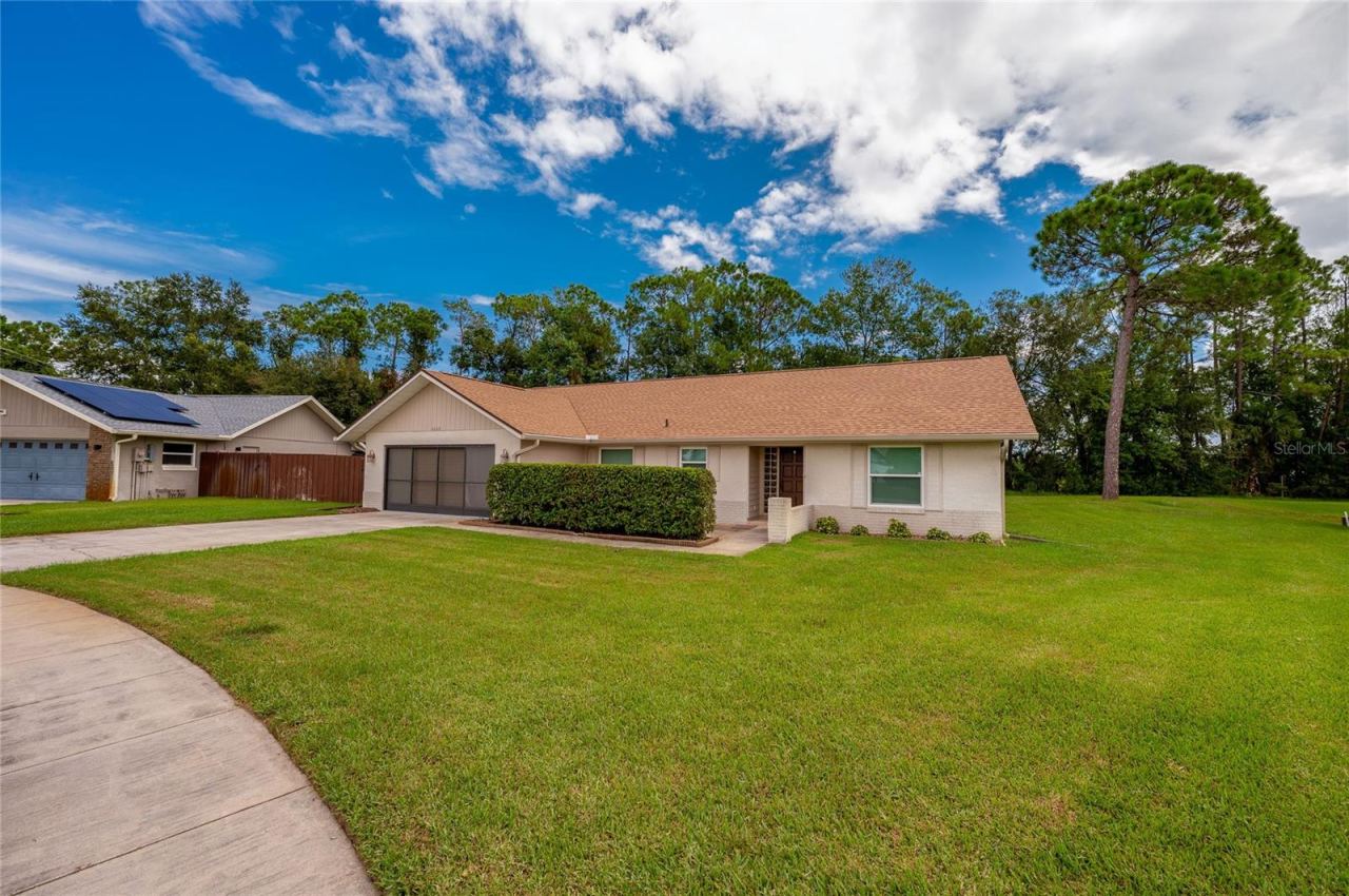 Photo 2 of 20: Charming single-story exterior showcasing a wide paved driveway, manicured green lawn, and low-maintenance landscaping.