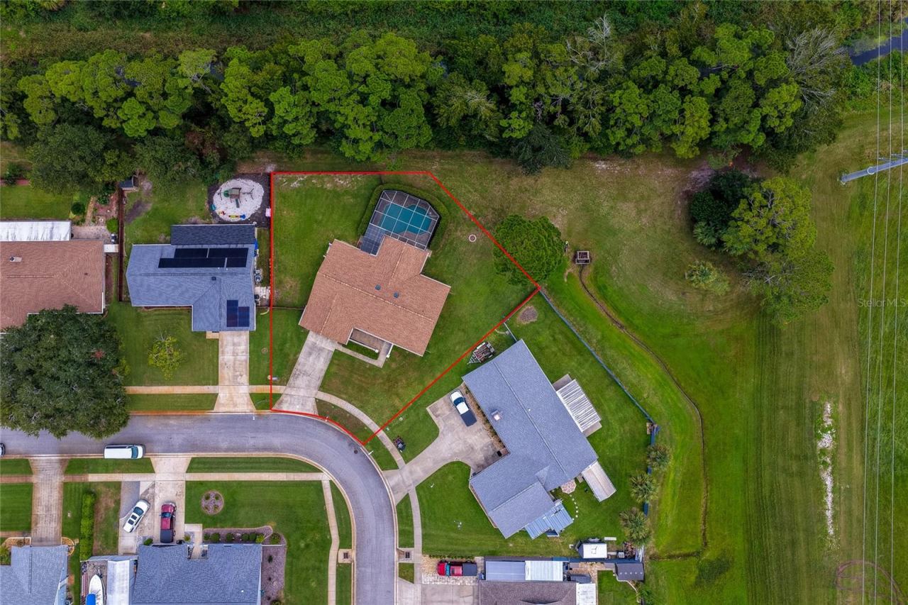 Photo 3 of 20: Overhead aerial shot outlining the expansive property boundary, screened pool enclosure, and surrounding green spaces.