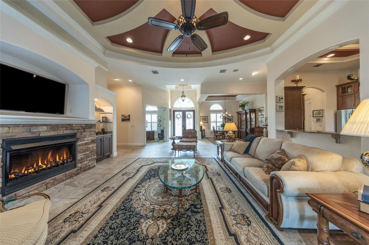 Photo 10 of 20: Step Into An Expansive Open-Concept Living Area Featuring A Custom Circular Tray Ceiling, Stacked Stone Gas Fireplace